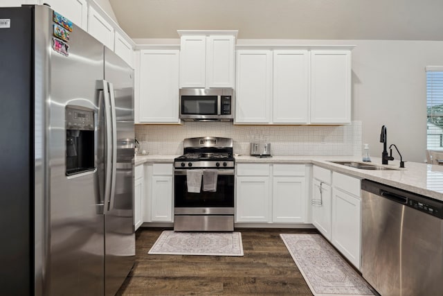 kitchen with stainless steel appliances, white cabinetry, light stone countertops, and sink