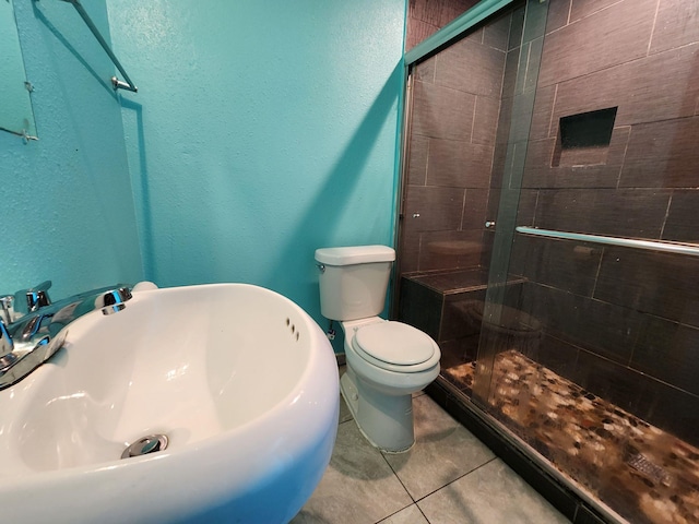 bathroom with a shower with shower door, toilet, tile patterned flooring, and sink