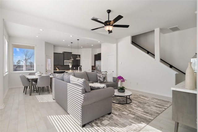 living room featuring ceiling fan, light hardwood / wood-style floors, and sink