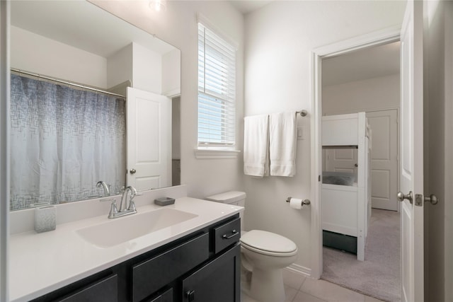 bathroom featuring a healthy amount of sunlight, toilet, tile patterned flooring, and vanity