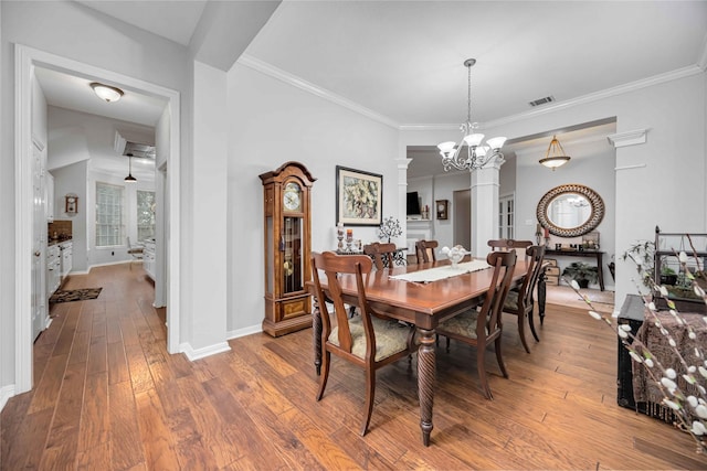 dining space with an inviting chandelier, hardwood / wood-style floors, ornamental molding, and ornate columns