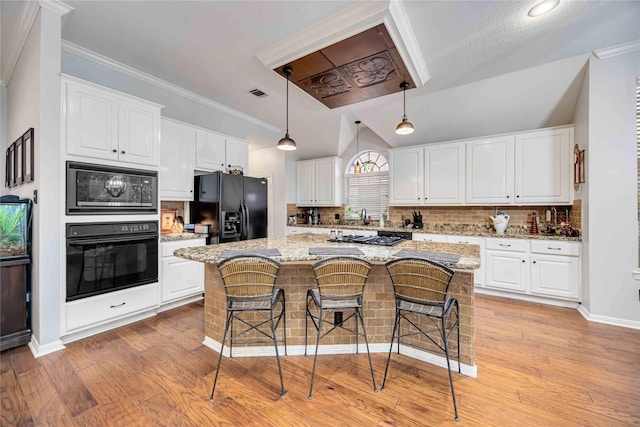 kitchen with pendant lighting, white cabinets, a kitchen island, and black appliances