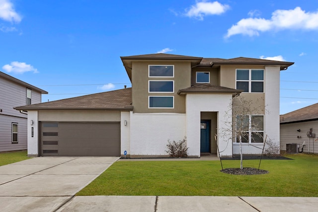 prairie-style house with a garage, a front lawn, and central air condition unit