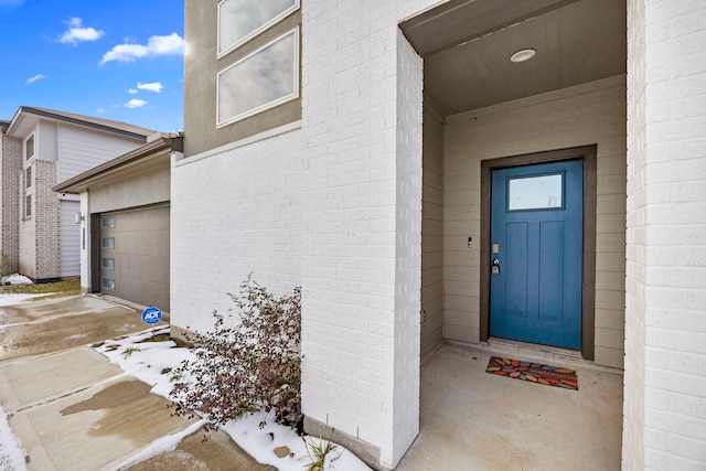 snow covered property entrance featuring a garage