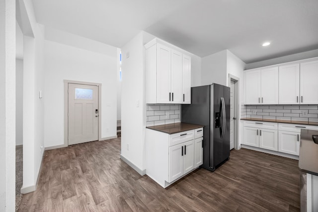 kitchen with white cabinetry, backsplash, and stainless steel fridge