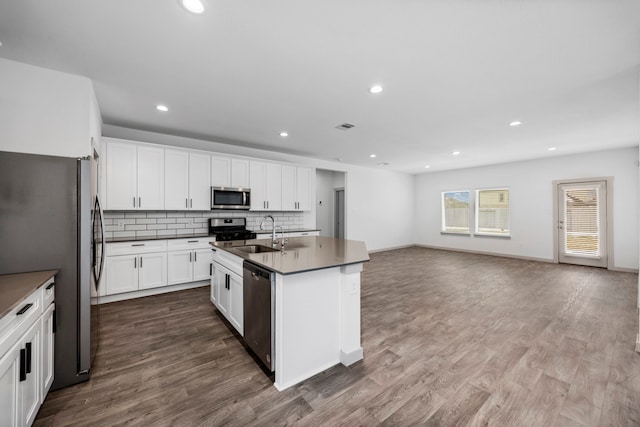 kitchen with an island with sink, sink, white cabinets, backsplash, and stainless steel appliances