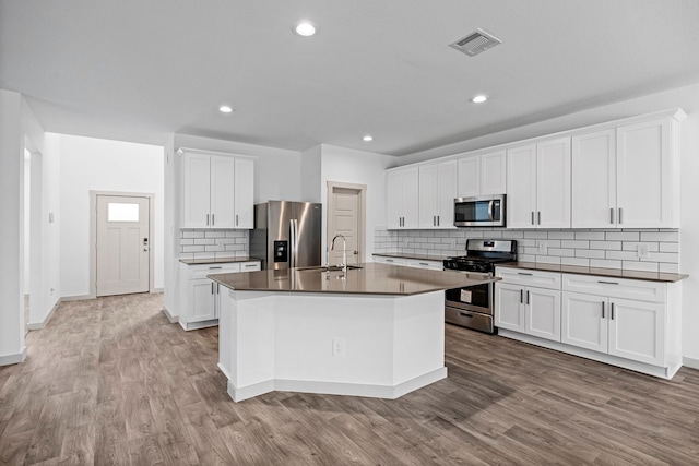 kitchen featuring appliances with stainless steel finishes, tasteful backsplash, sink, white cabinets, and a kitchen island with sink