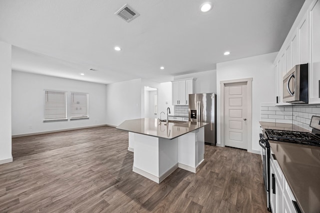 kitchen featuring appliances with stainless steel finishes, a breakfast bar, sink, white cabinets, and a kitchen island with sink