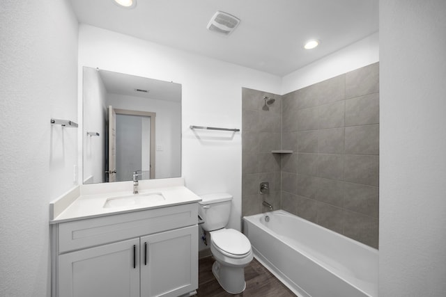 full bathroom featuring tiled shower / bath combo, vanity, hardwood / wood-style flooring, and toilet