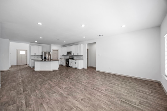 kitchen with white cabinetry, tasteful backsplash, a center island with sink, stainless steel appliances, and light hardwood / wood-style floors