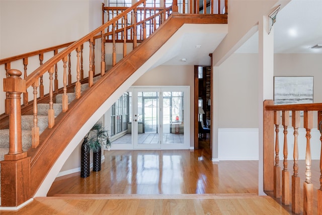 stairs featuring hardwood / wood-style floors and a towering ceiling