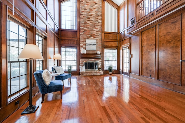 living room with wood-type flooring, a large fireplace, a high ceiling, and wood walls