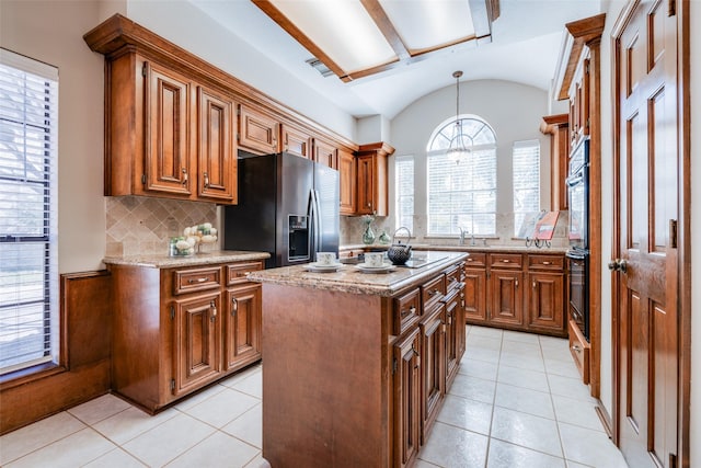 kitchen with decorative light fixtures, lofted ceiling, a center island, stainless steel refrigerator with ice dispenser, and light stone countertops