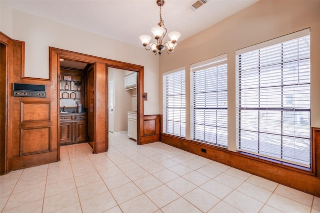 unfurnished dining area featuring light tile patterned floors and a chandelier