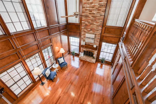 living room with ceiling fan, a healthy amount of sunlight, hardwood / wood-style floors, and a fireplace