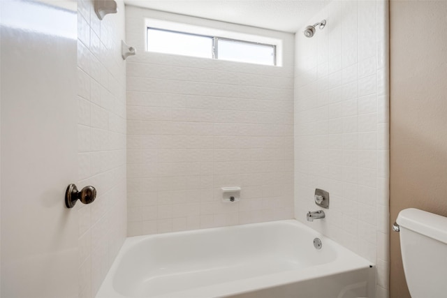 bathroom featuring toilet and tiled shower / bath combo