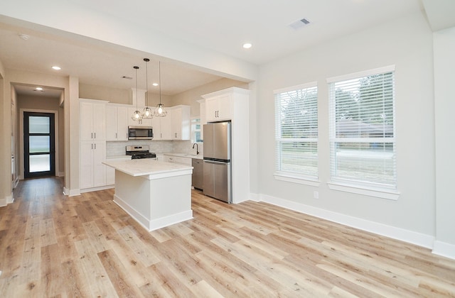 kitchen with pendant lighting, white cabinetry, appliances with stainless steel finishes, and a kitchen island