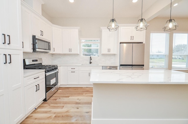 kitchen with sink, decorative light fixtures, stainless steel appliances, and white cabinets