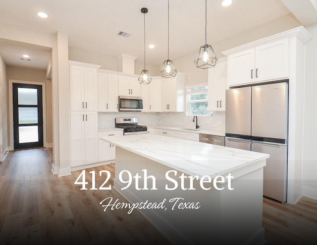 kitchen with white cabinetry, appliances with stainless steel finishes, a center island, and decorative light fixtures