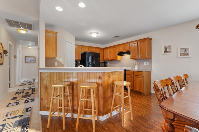 16527 Nassau Way, Jamaica Beach, TX 77554 - kitchen with light countertops, black fridge with ice dispenser, under cabinet range hood, a breakfast bar, and visible vents