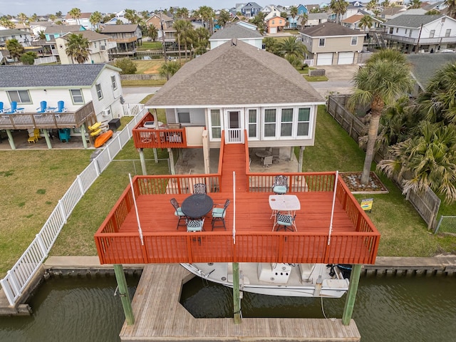 exterior space featuring a lawn, a deck with water view, a residential view, and a shingled roof