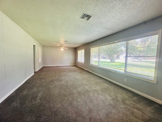 empty room with ceiling fan, dark carpet, and a textured ceiling