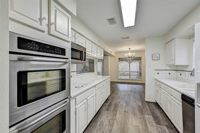 kitchen featuring stainless steel appliances, white cabinetry, an inviting chandelier, and decorative backsplash