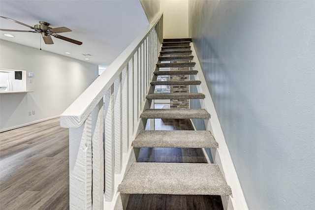 stairs featuring hardwood / wood-style flooring and ceiling fan