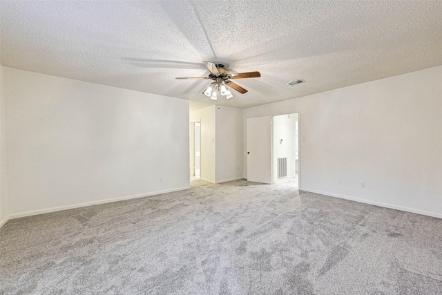 spare room featuring ceiling fan, light colored carpet, and a textured ceiling