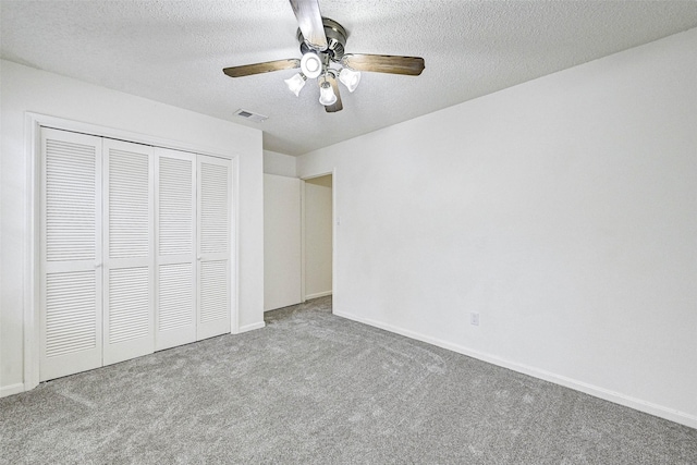 unfurnished bedroom featuring ceiling fan, a closet, light carpet, and a textured ceiling