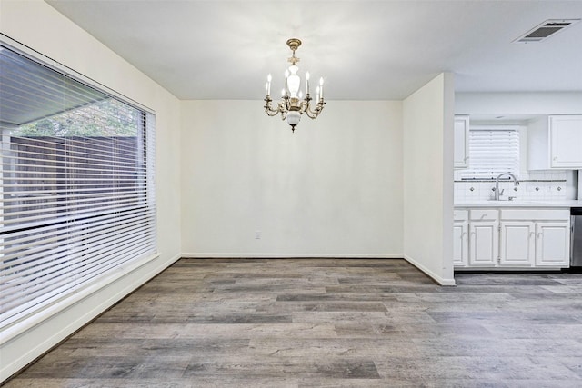 unfurnished dining area featuring a chandelier, sink, and light hardwood / wood-style flooring