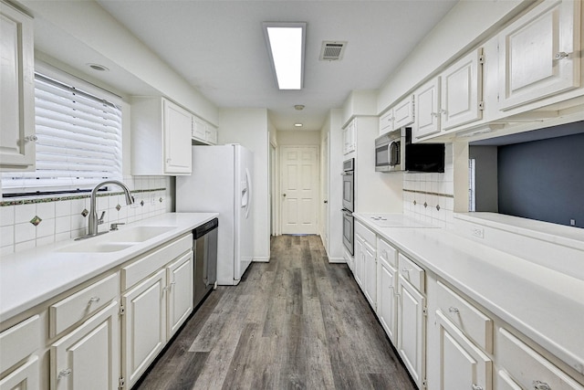 kitchen with sink, dark wood-type flooring, stainless steel appliances, white cabinets, and decorative backsplash