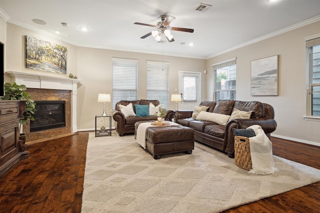 living room featuring ornamental molding, ceiling fan, a fireplace, and light wood-type flooring