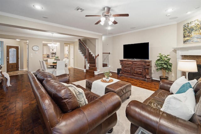 living room with a fireplace, crown molding, ceiling fan with notable chandelier, and hardwood / wood-style flooring