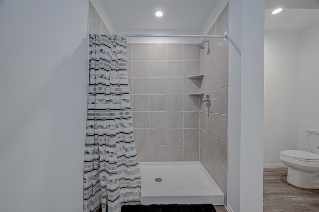 bathroom with wood-type flooring, curtained shower, and toilet