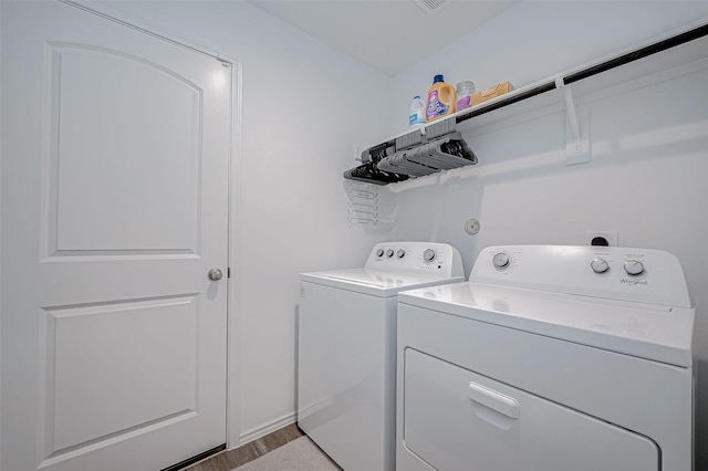 laundry area with washing machine and dryer and light hardwood / wood-style floors