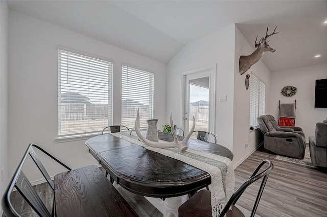 dining space with lofted ceiling, hardwood / wood-style floors, and plenty of natural light