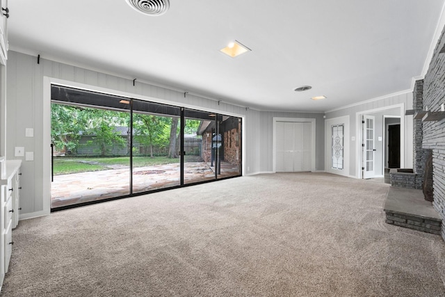 unfurnished living room with ornamental molding, a brick fireplace, and carpet floors