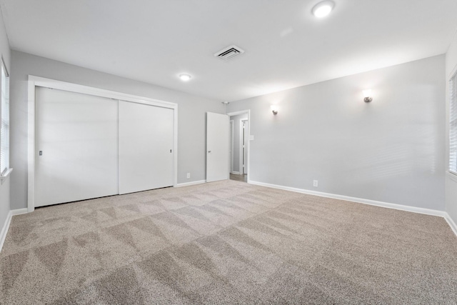 unfurnished bedroom featuring light colored carpet and a closet