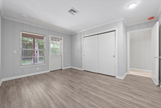 unfurnished bedroom with ornamental molding, a closet, and light wood-type flooring