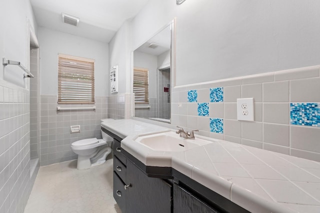 bathroom featuring tile patterned floors, toilet, vanity, and tile walls