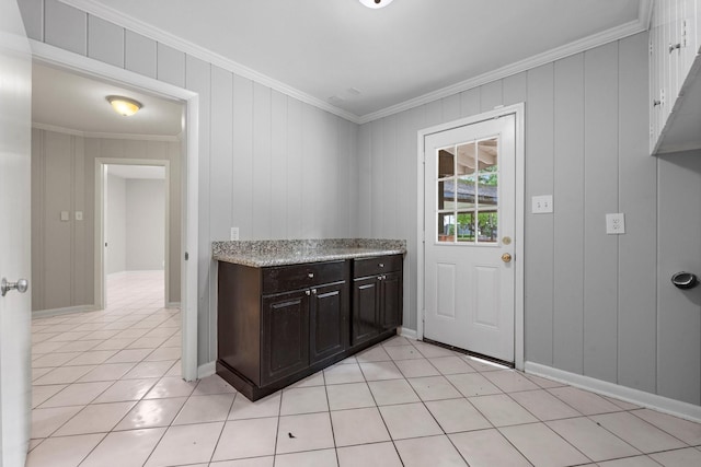 kitchen featuring dark brown cabinetry, crown molding, wood walls, and light tile patterned flooring