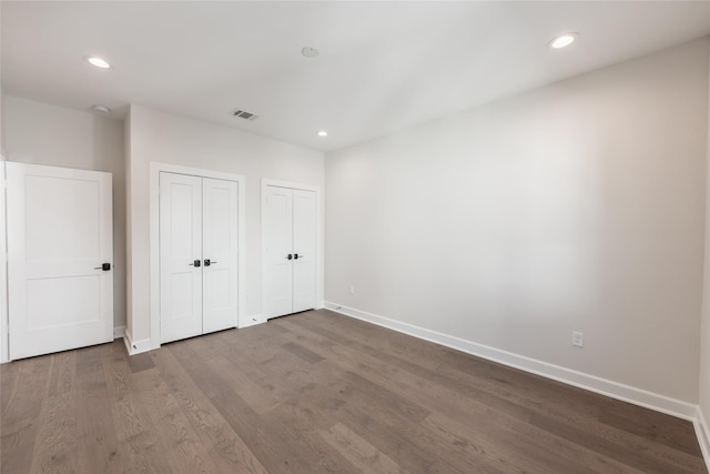 unfurnished bedroom featuring hardwood / wood-style flooring and two closets