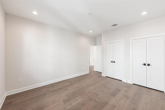 unfurnished bedroom featuring multiple closets and light hardwood / wood-style floors