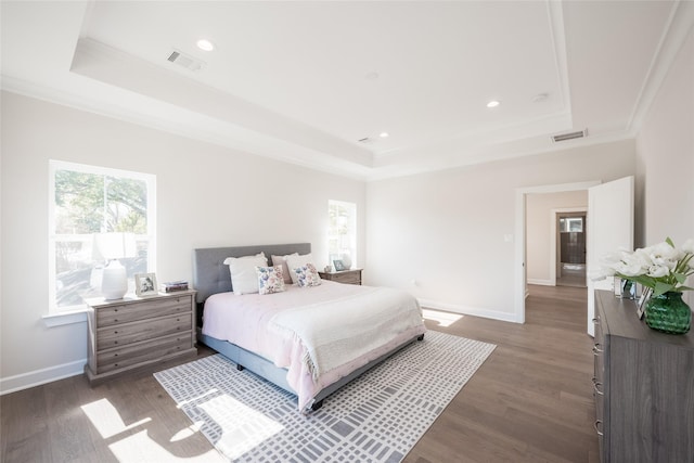 bedroom with ornamental molding, dark hardwood / wood-style flooring, and a raised ceiling