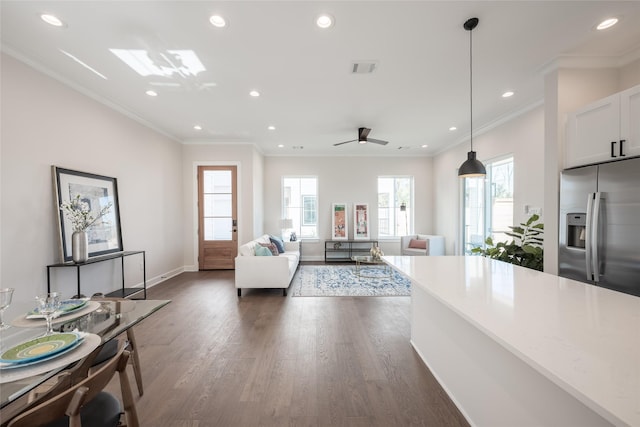 living room featuring crown molding, ceiling fan, dark hardwood / wood-style flooring, and a skylight