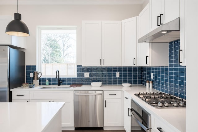 kitchen featuring pendant lighting, sink, appliances with stainless steel finishes, white cabinetry, and tasteful backsplash