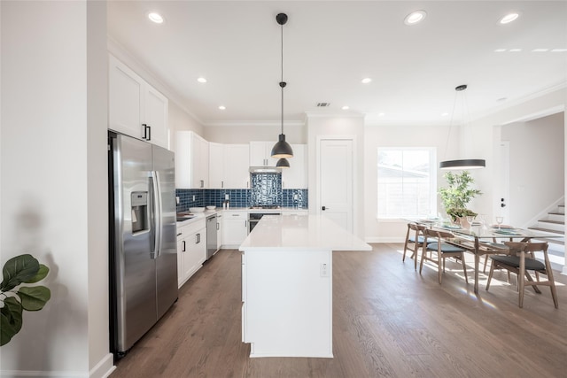 kitchen featuring white cabinetry, stainless steel appliances, decorative light fixtures, and a center island