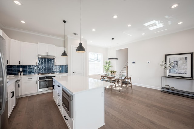 kitchen featuring a kitchen island, white cabinets, dark hardwood / wood-style flooring, hanging light fixtures, and stainless steel appliances