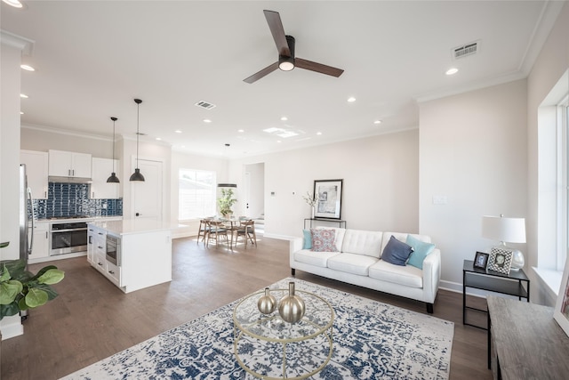 living room featuring ornamental molding, dark wood-type flooring, and ceiling fan